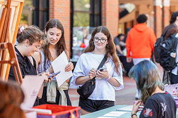 Students browse artwork and interact with a vendor during the SUAB Arts Festival, an annual event that gives Oklahoma State University student artists a chance to showcase their work and connect with the campus community.