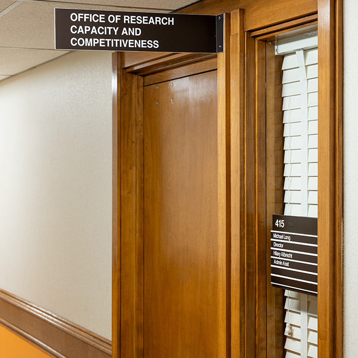 A hallway entrance with wood-framed doors and signage identifying the Office of Research Capacity and Competitiveness.