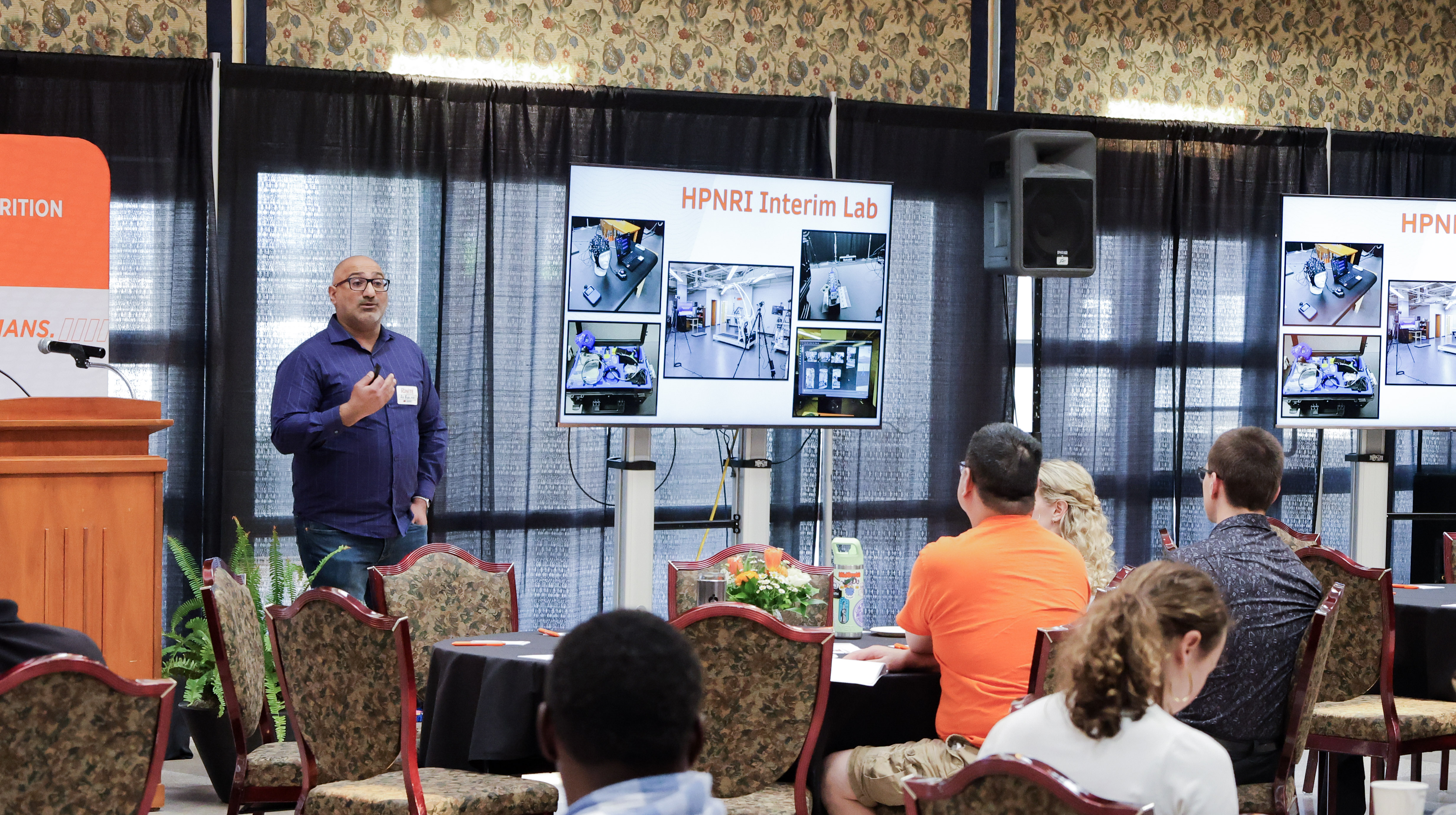 Dr. Ali Boolani, HPNRI associate director of research and strategic initiatives, presents to a room of people. 