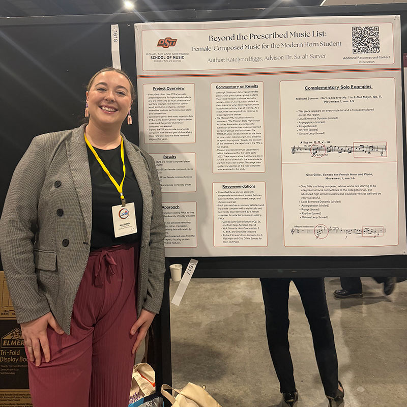 A student stands in front of their research poster