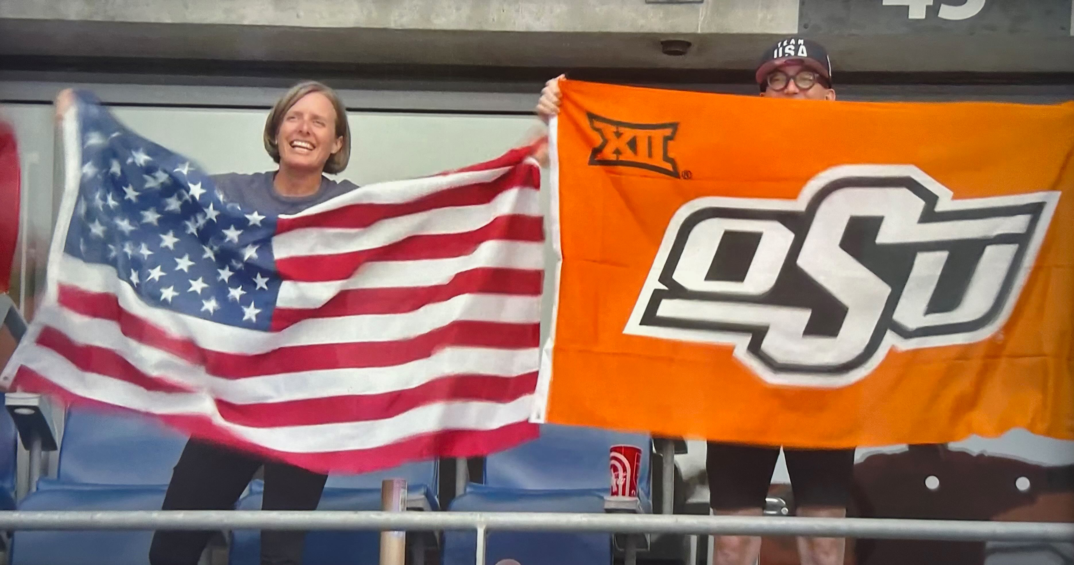 Two people, one holding an OSU flag, the other a USA flag.