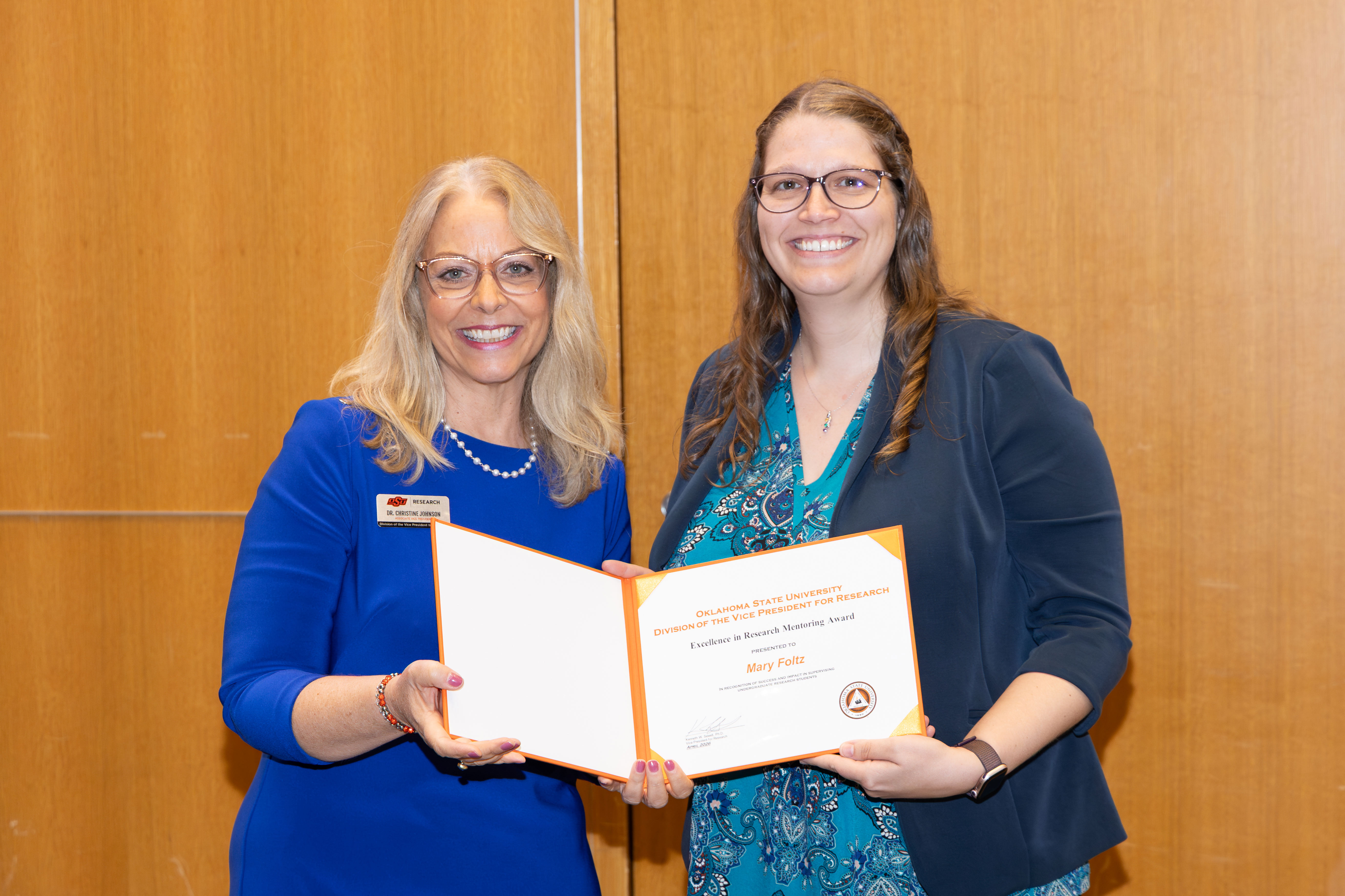 two women stand holding a certificate