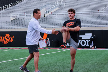 A coach demonstrates proper stretching techniques during a warm-up