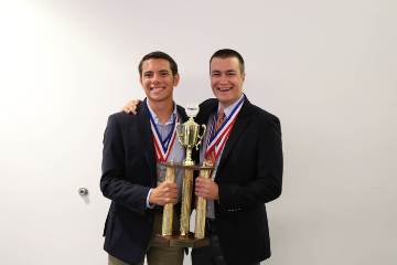 Two Aggies holding their championship trophy