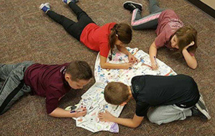 Children drawing on a dress at Blackwell Elementary