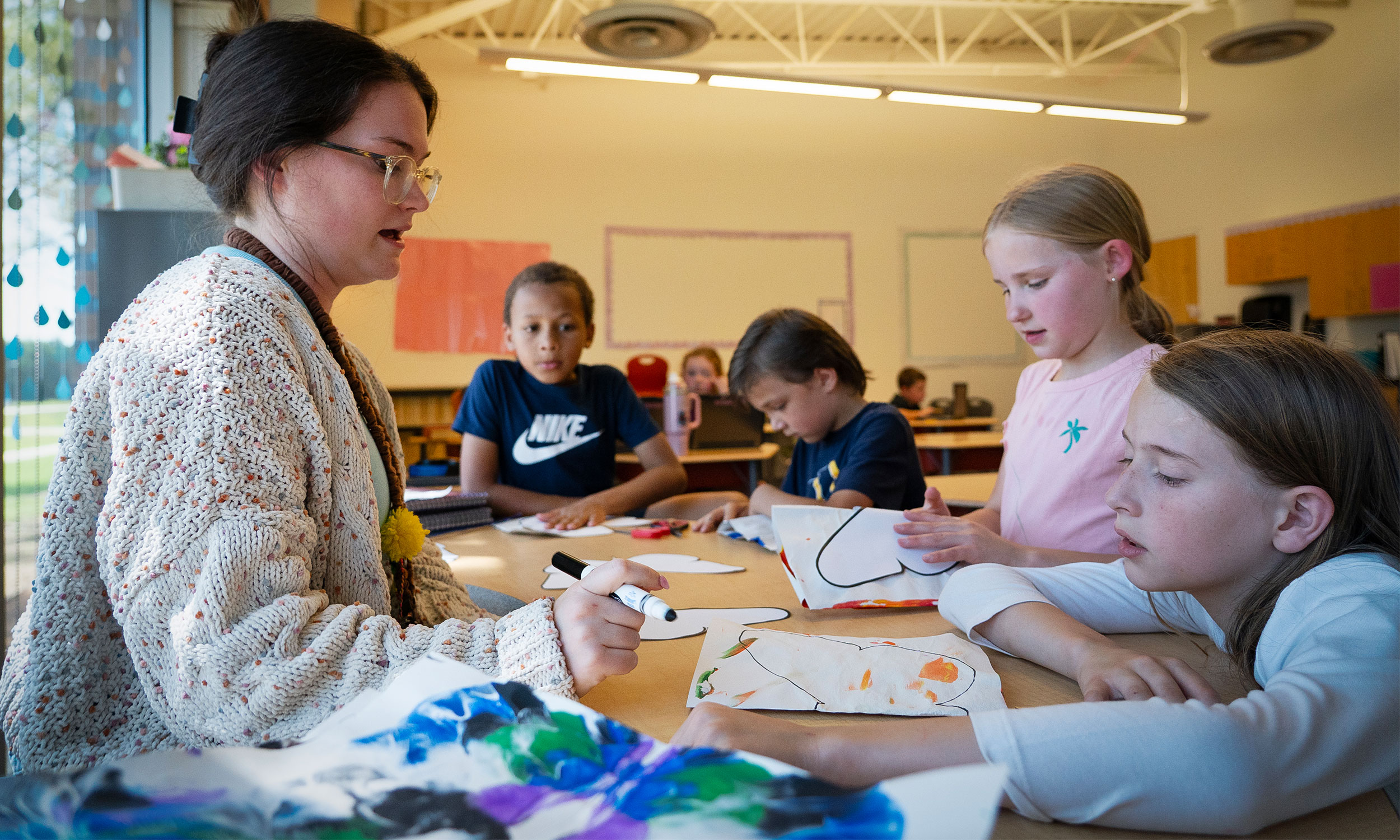 Ms. Gabbie Briscoe leads small group of students in classroom project.