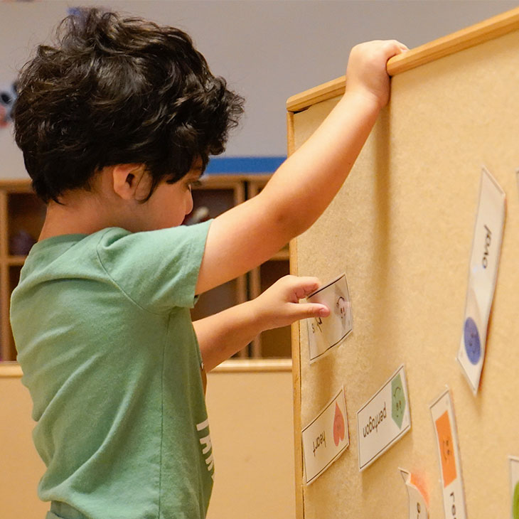 Boy sorts sight words on corkboard