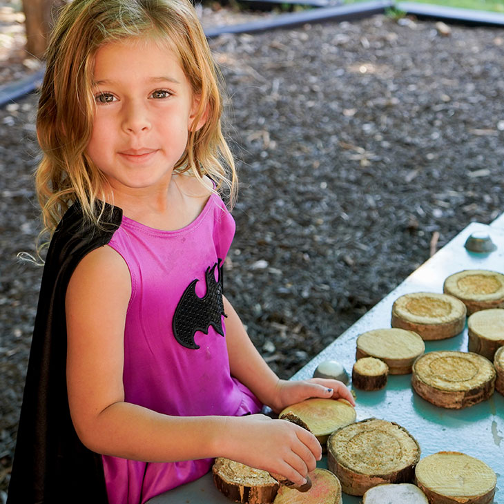 Girl sorts wood discs on playground