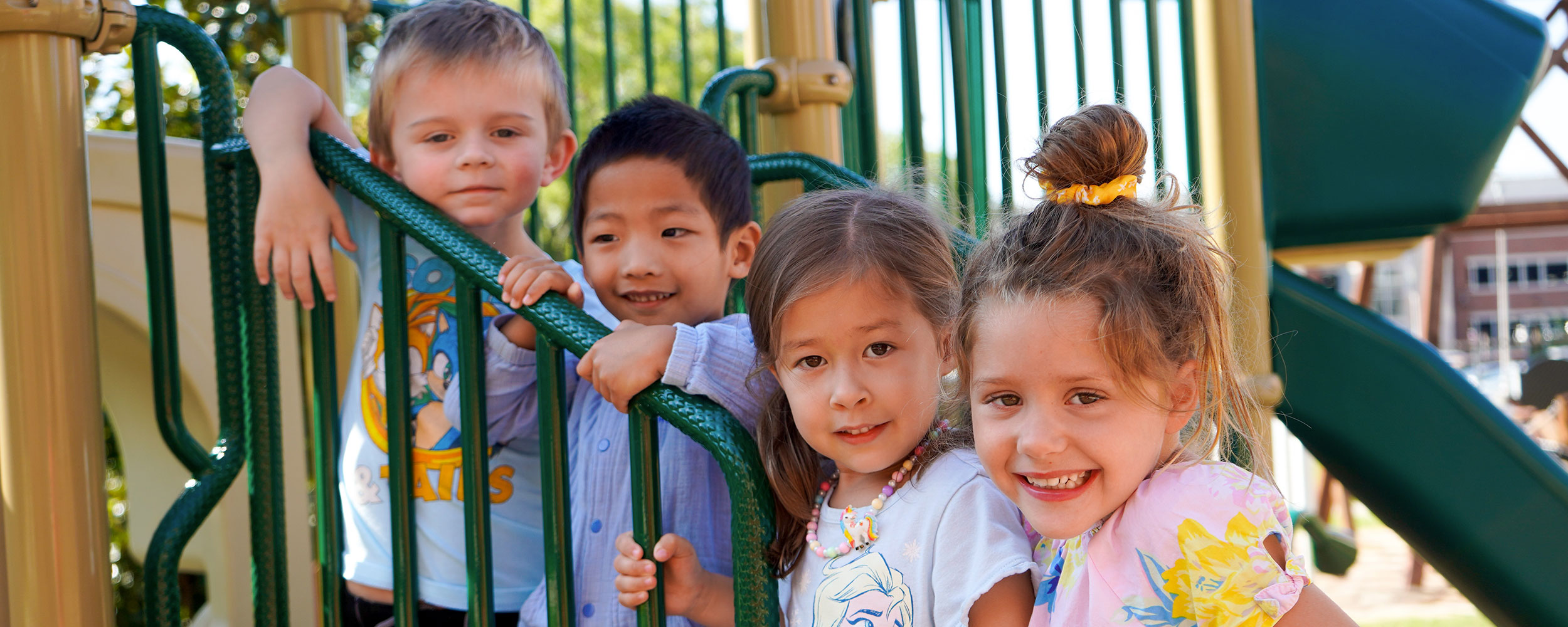 4 CDL students smiling at camera from playground steps