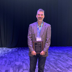 Dr. Scott Haselwood stands with award