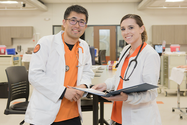 Male and female nurse smile for photo in clinical setting