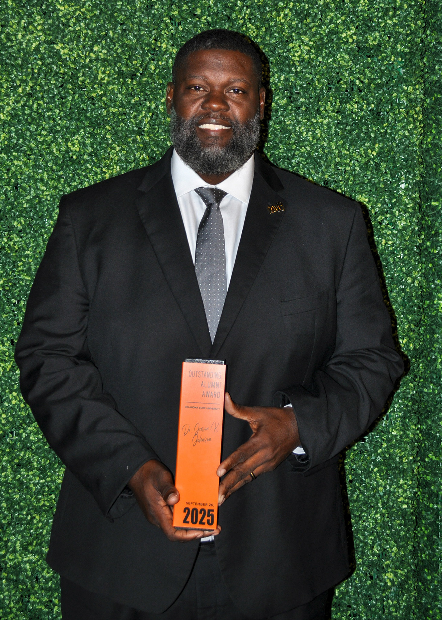 Dr. Jason Johnson holding Outstanding Alumni award