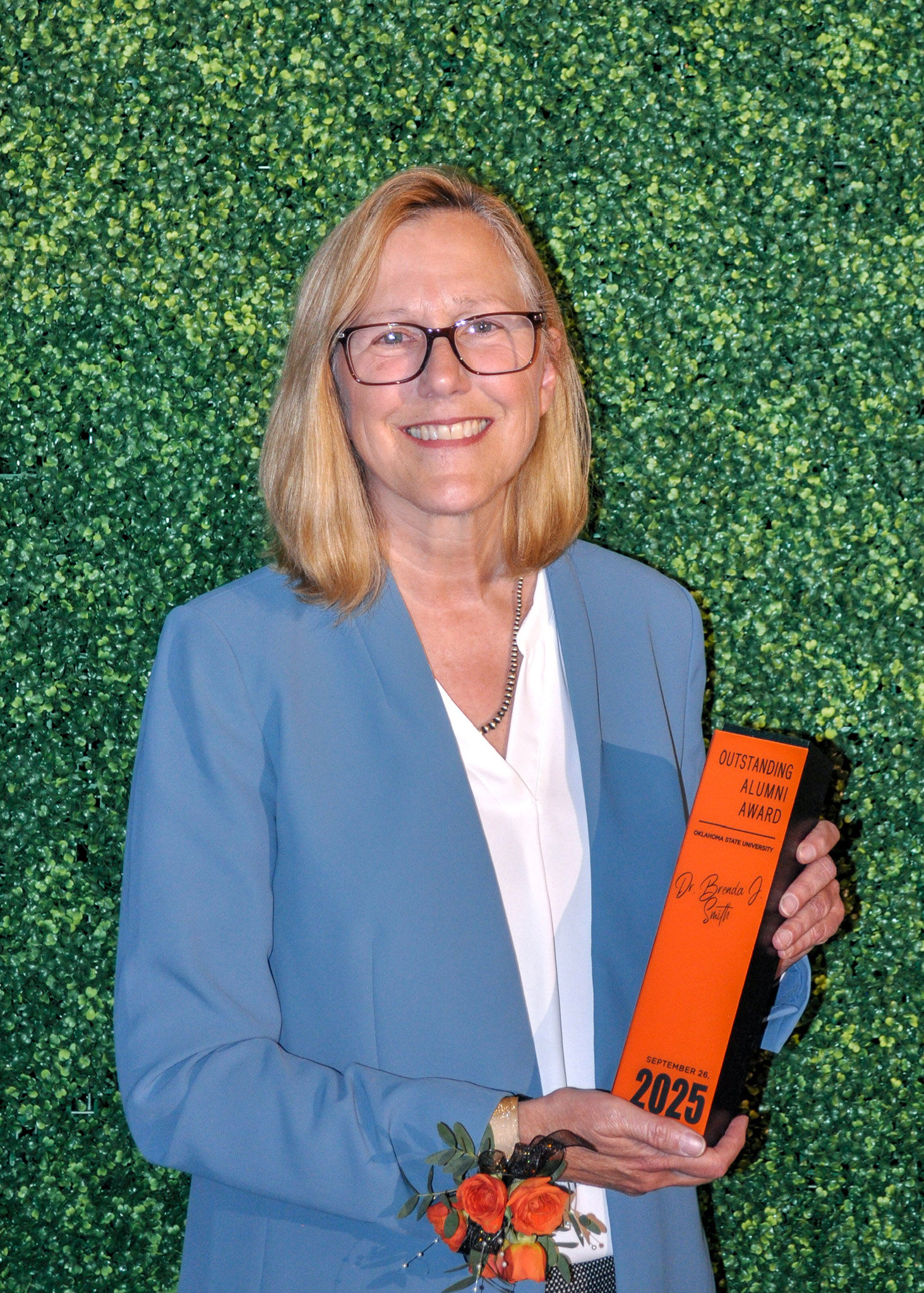 Dr. Brenda Smith holding Outstanding Alumni award