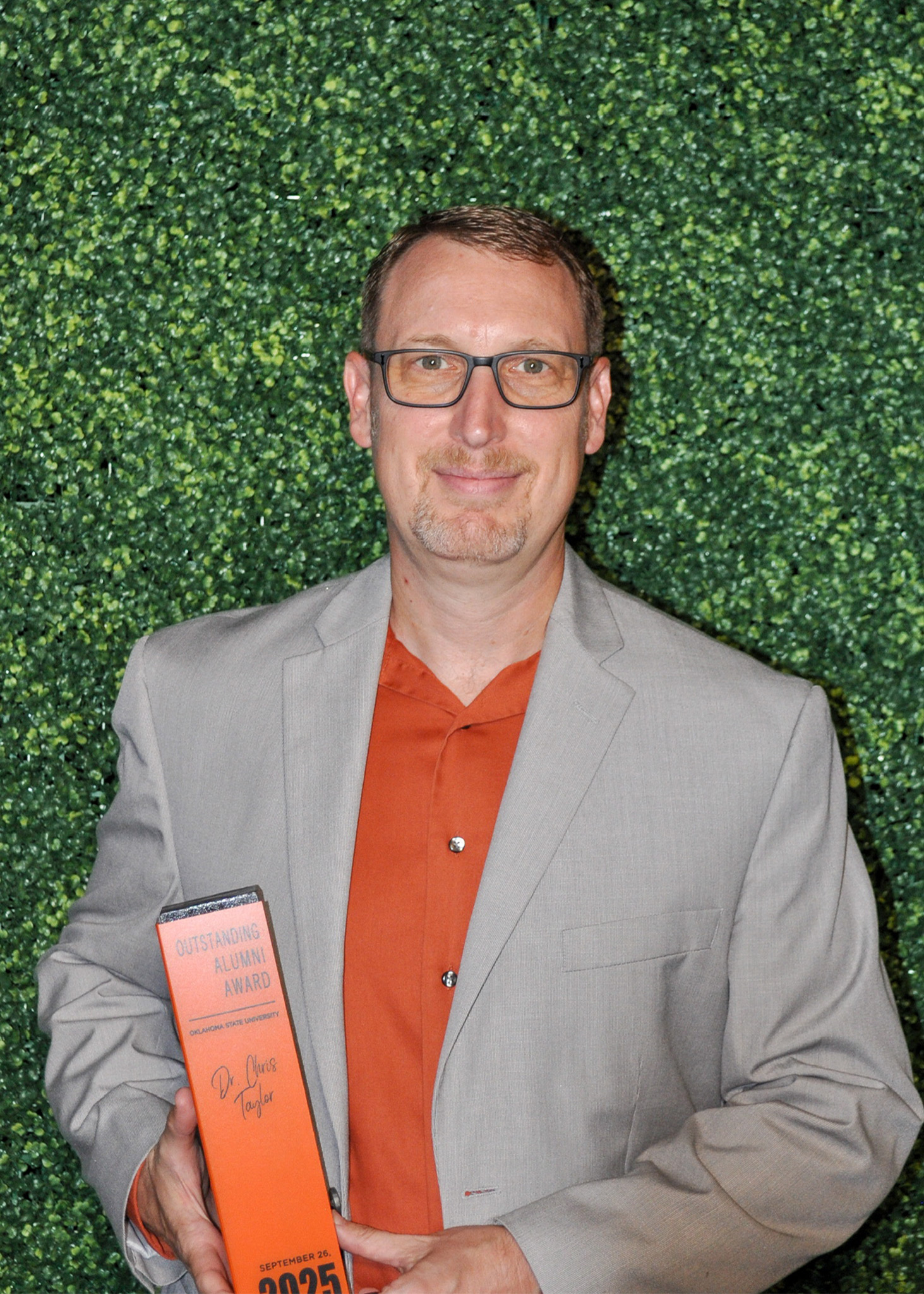 Dr. Christopher Taylor holding Outstanding Alumni award