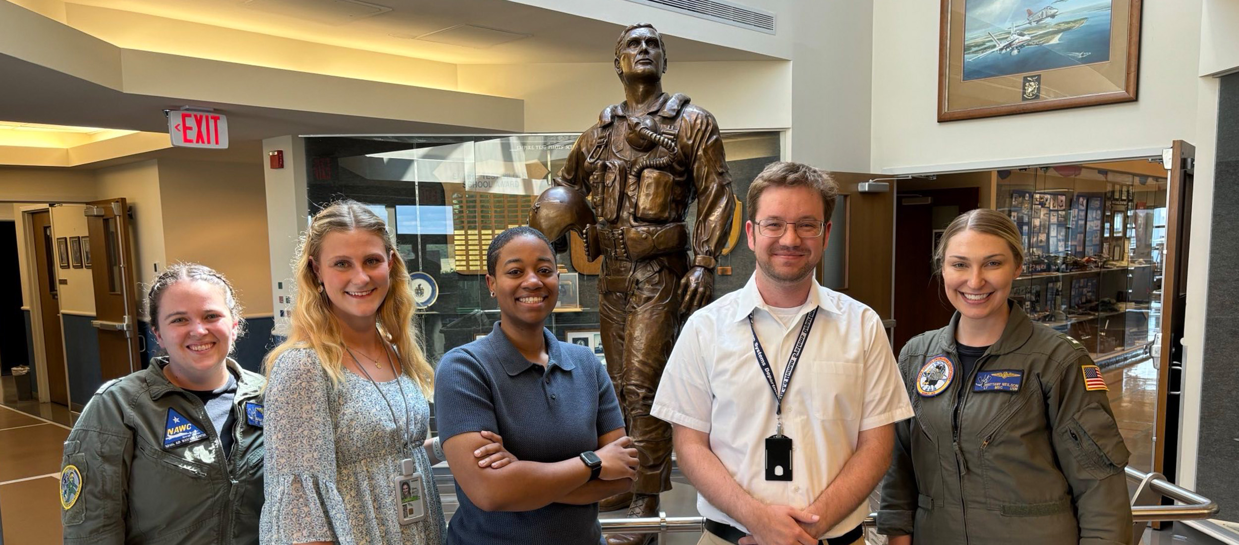 A group of people is shown in front of the statue of a famous test pilot.