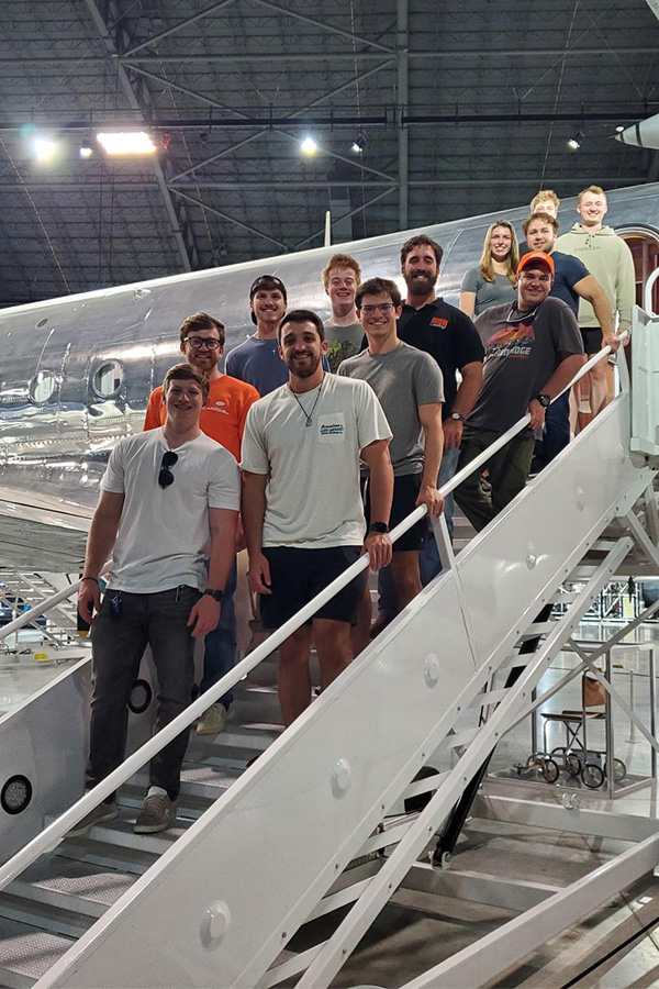 A diverse group of individuals gathered on the stairs of an airplane, taking in the sites of the National Air Force Museum.