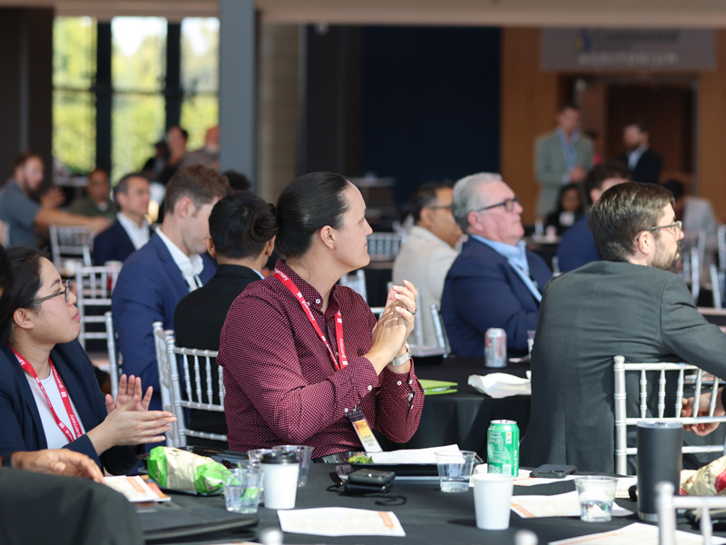 An attendee of the conference applauding while looking towards a presenter.