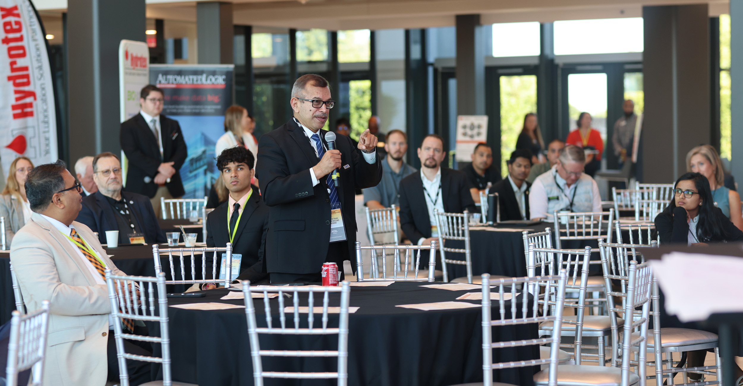 Hosts and attendees of the GPCoE conference stand together discussing something with large smiles on their faces.