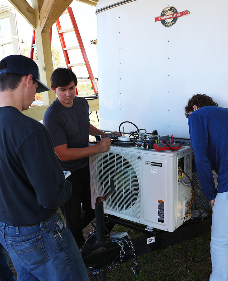 Several men engaged in maintenance work on a white air conditioner, demonstrating teamwork and technical skills