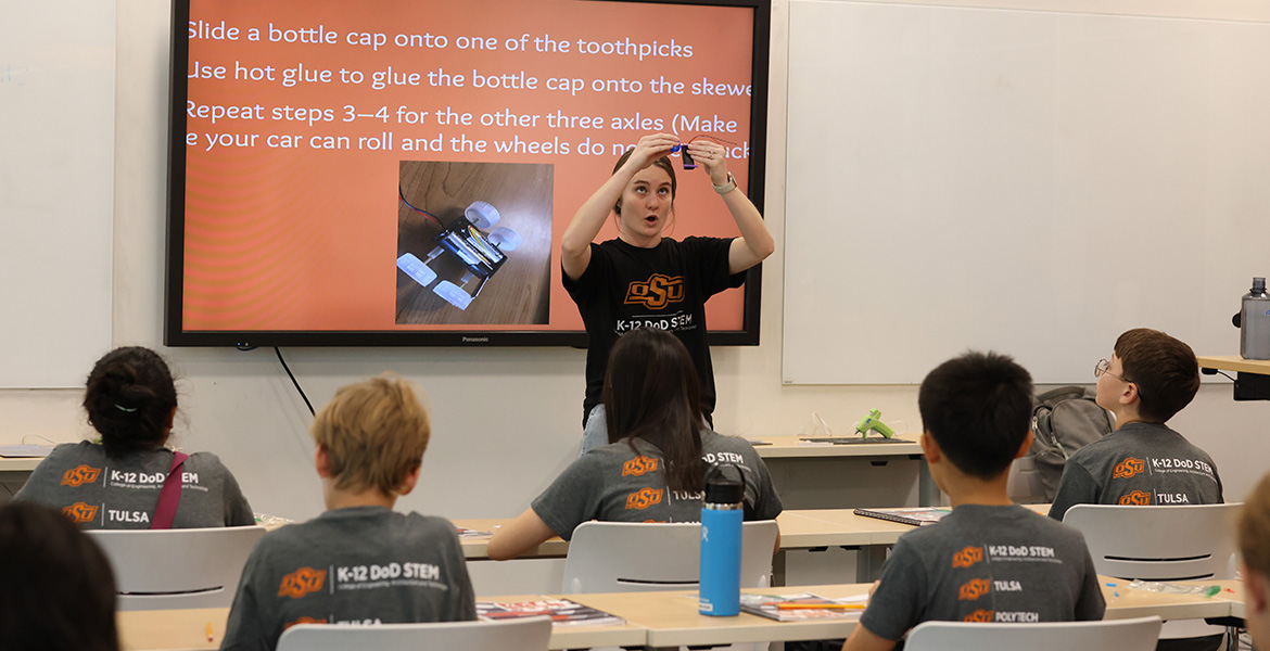 A CEAT student instructing young students how to build a robotic vehicle during a STEM event.