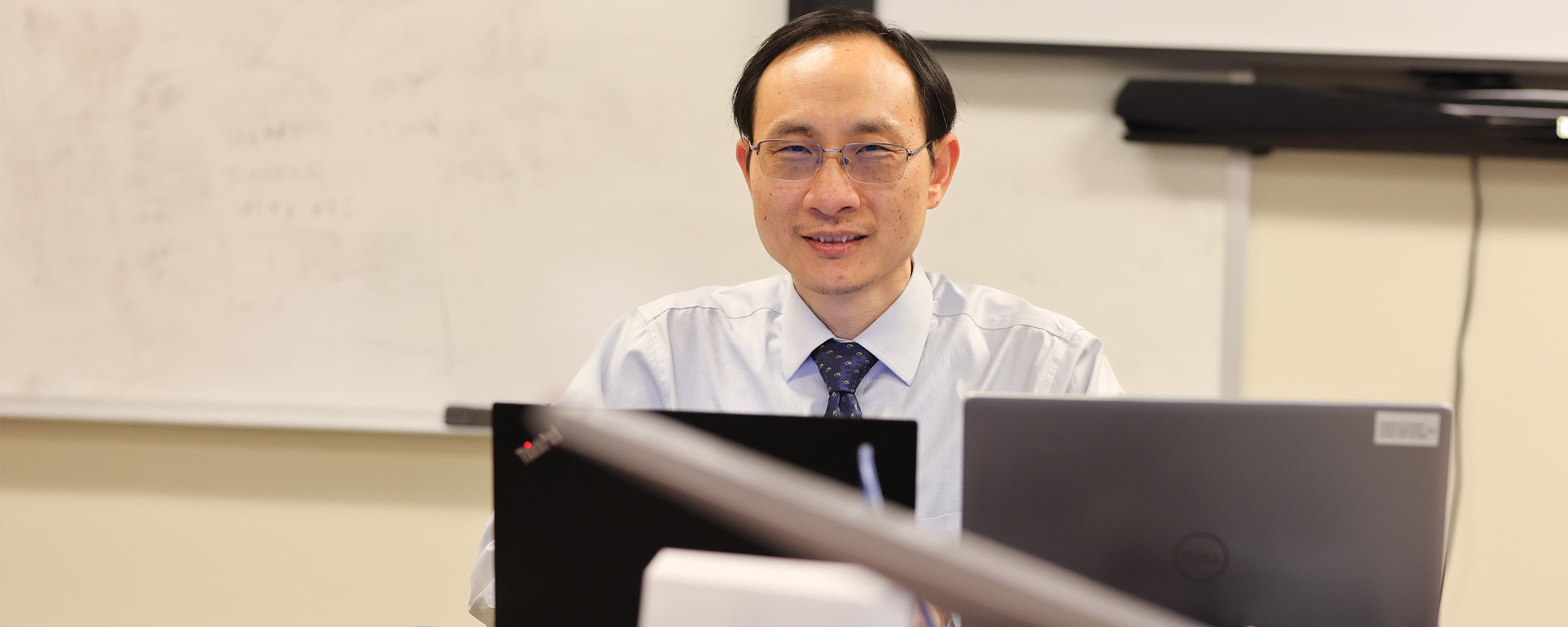 Dr. Joshua Li sits at his computer in his lab