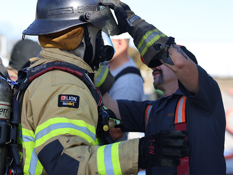 A firefighter is helped out of his gear by an instructor during a session of the Advanced Fire Behavior course taught by OSU Fire Service Training. 