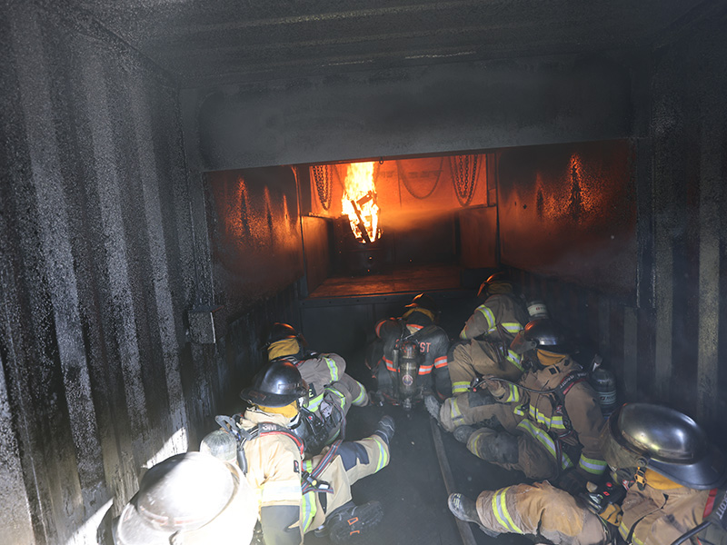 Firefighters taking the Advanced Fire Behavior course taught by OSU Fire Service Training sit in a mobile fire lab to experience temperatures similar to an active fire.