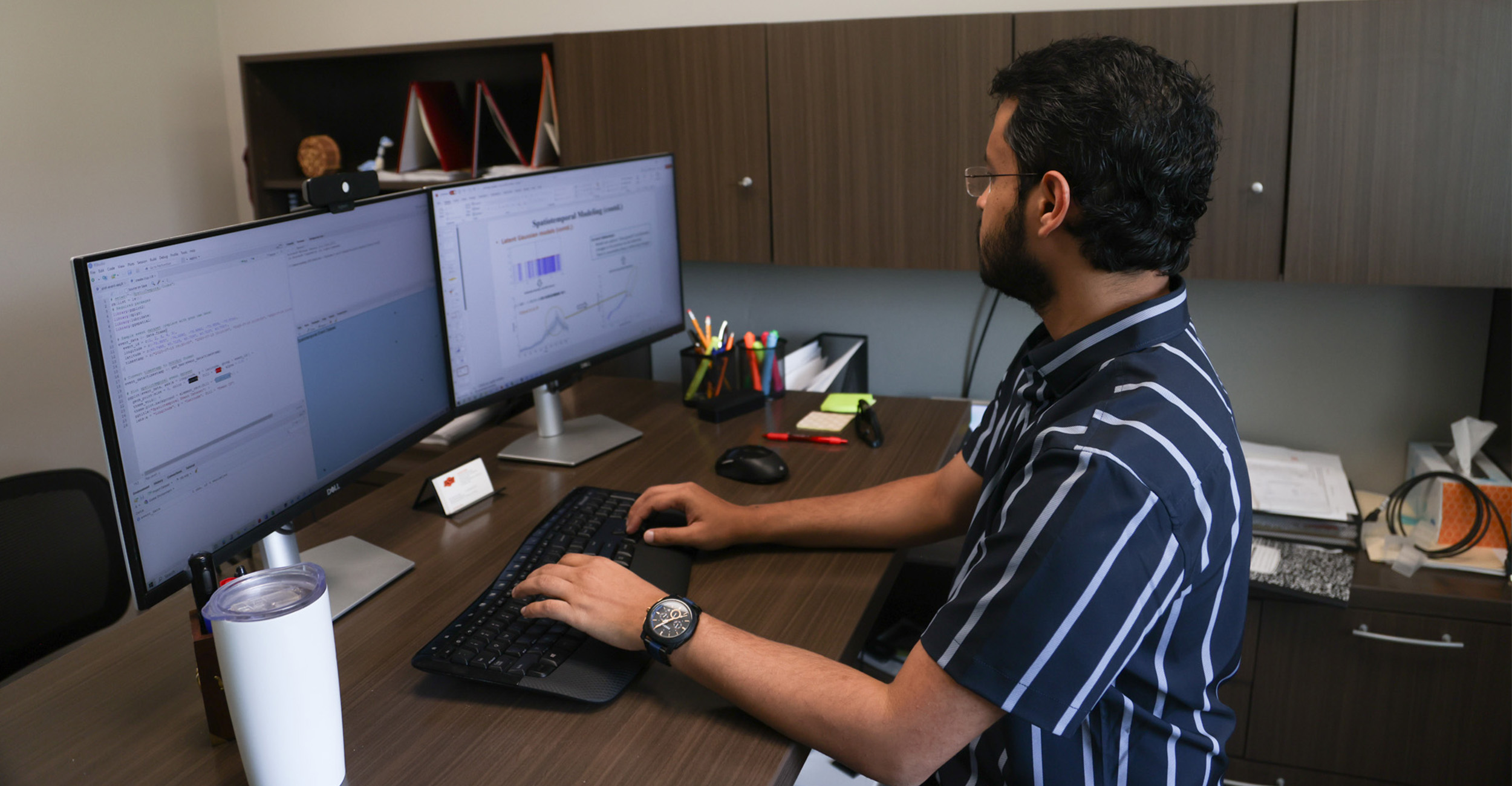 A man faces a computer screen with algorithms and data used for research.