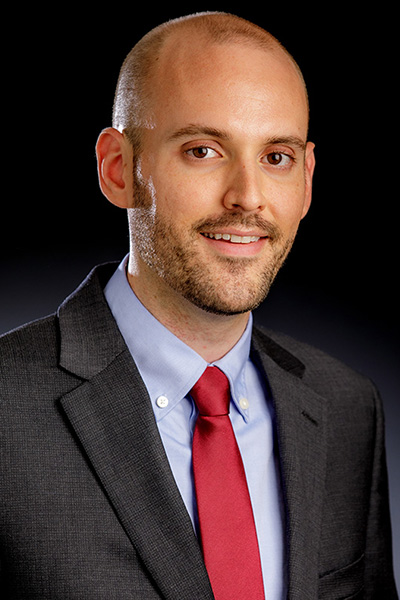 Dr. Austin Buchanan is pictured wearing a suit for his OSU faculty portrait.