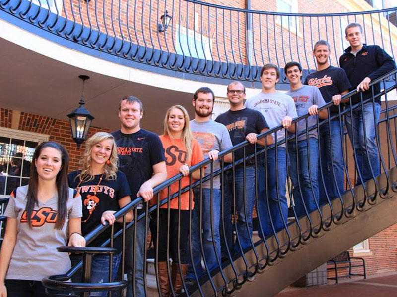 A group of college students pose on a spiral staircase for a photo op.