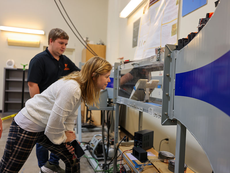 A researcher looking into a wind tunnel.