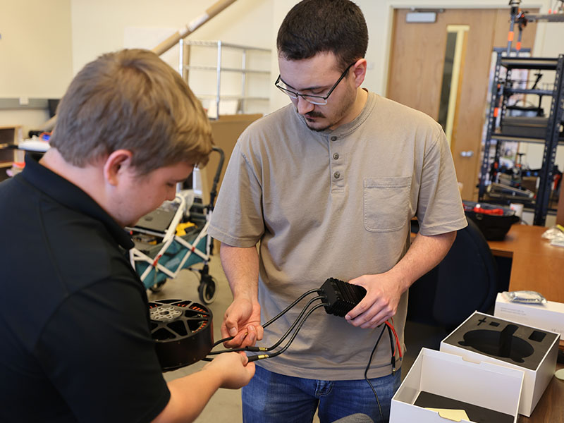 Two students working in the lab with equipment.