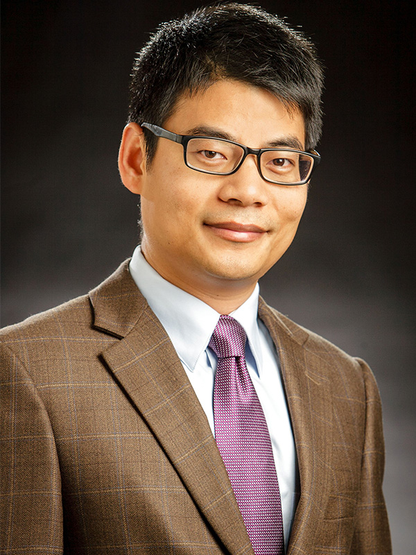 A headshot of a man in a brown suit.