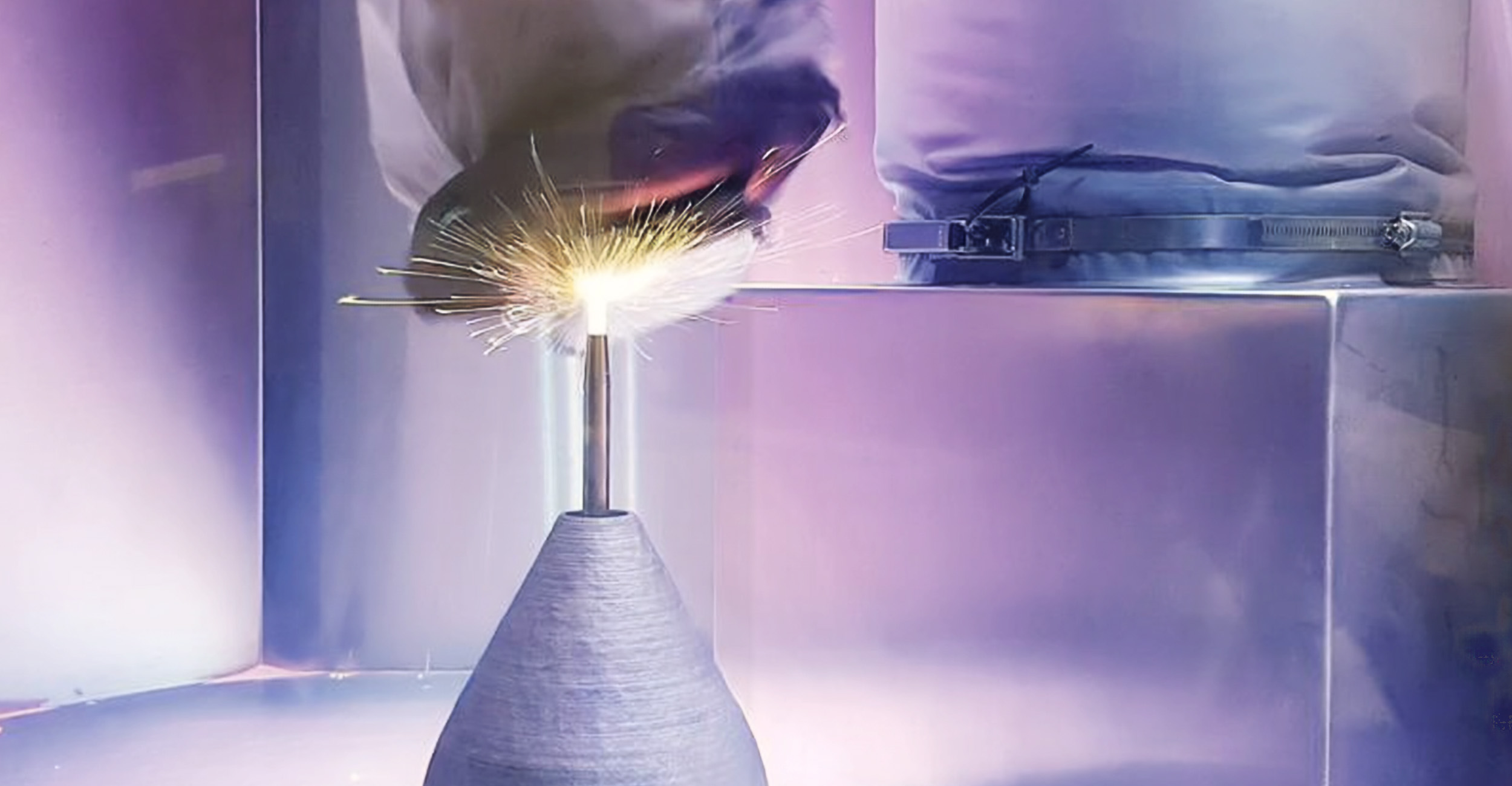 A close-up image of a cold spray system in action. Sparks can be seen from the nozzle of an advanced manufacturing system.