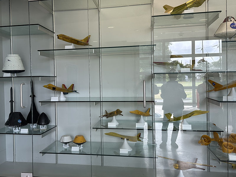 Aircraft models on display in a glass case at a NASA facility.