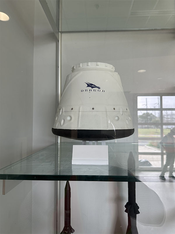A white object that is part of a spacecraft displayed in a glass case at a faciliity owned by NASA.