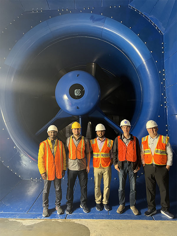 Members of the Kara Lab research team standing in front of a large blue turbine.