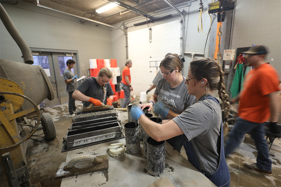 A group of students work with concrete in a laboratory setting.