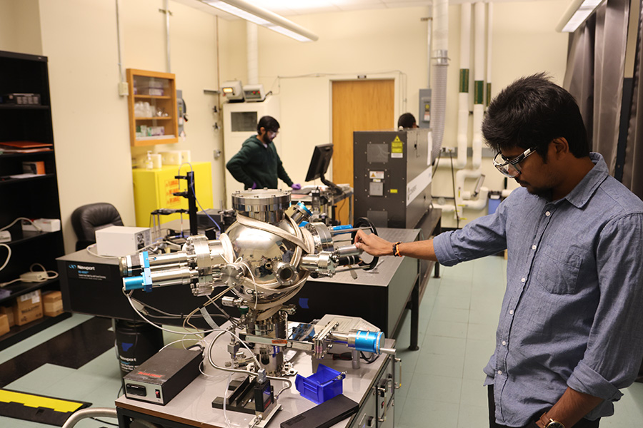 A man looks at a device used to study lasers. 