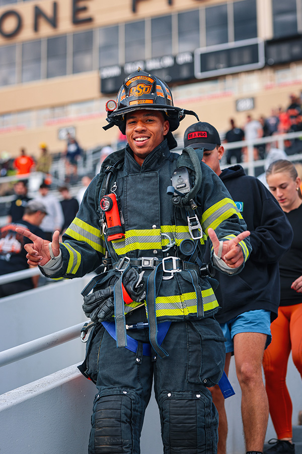 A man in full firefighter gear gives the "Go Pokes" sign during the eighth annual 9/11 Memorial Stair Climb hosted by OSU.