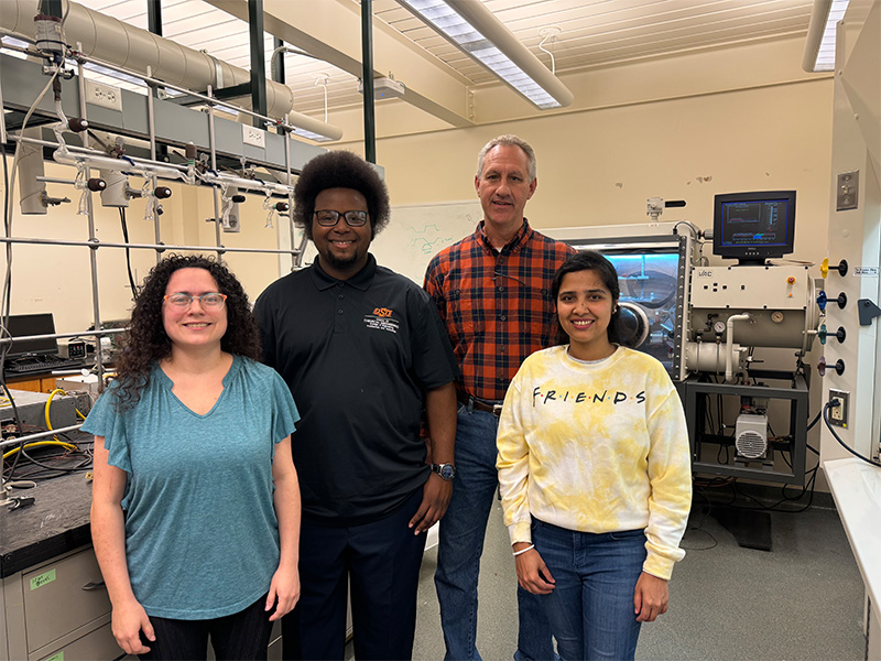 Four people standing in a chemical engineering lab.