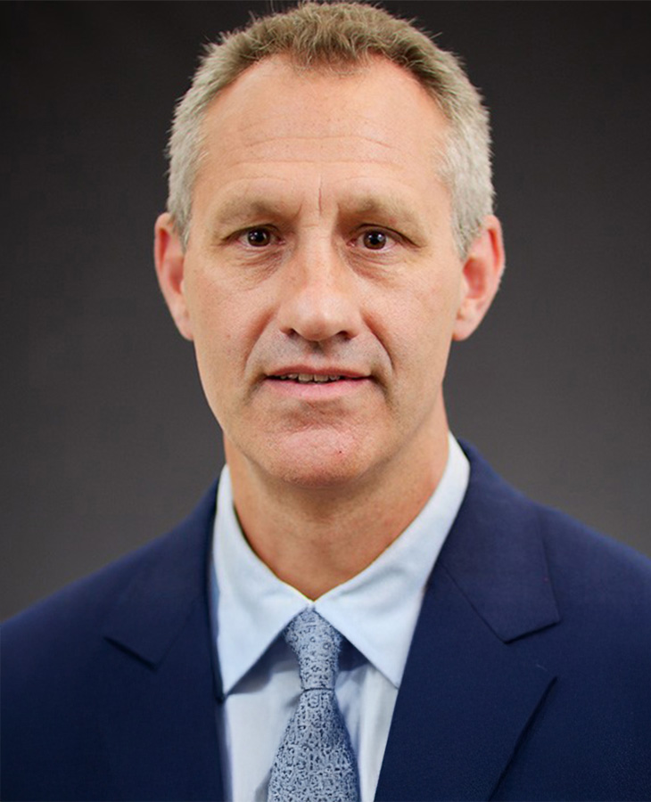 A headshot of a man in a blue suit.