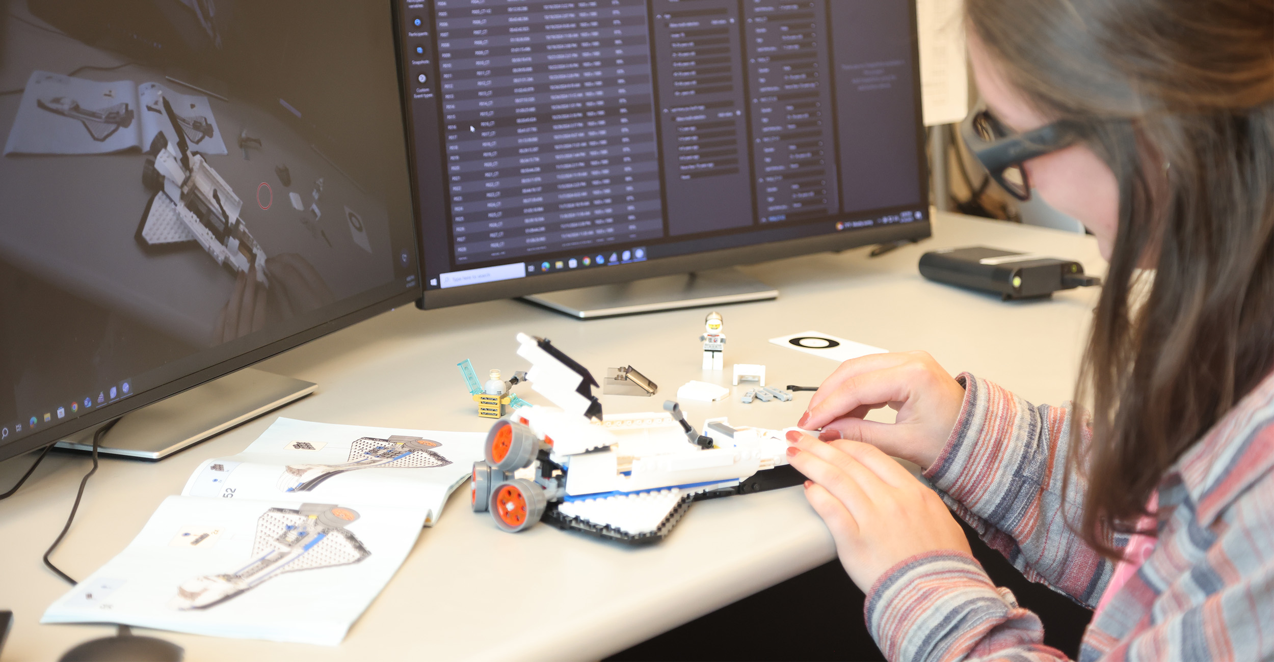 A female wearing eye tracking software assembles a Lego rocket with the objects motions being tracked on the computer screen in the background.