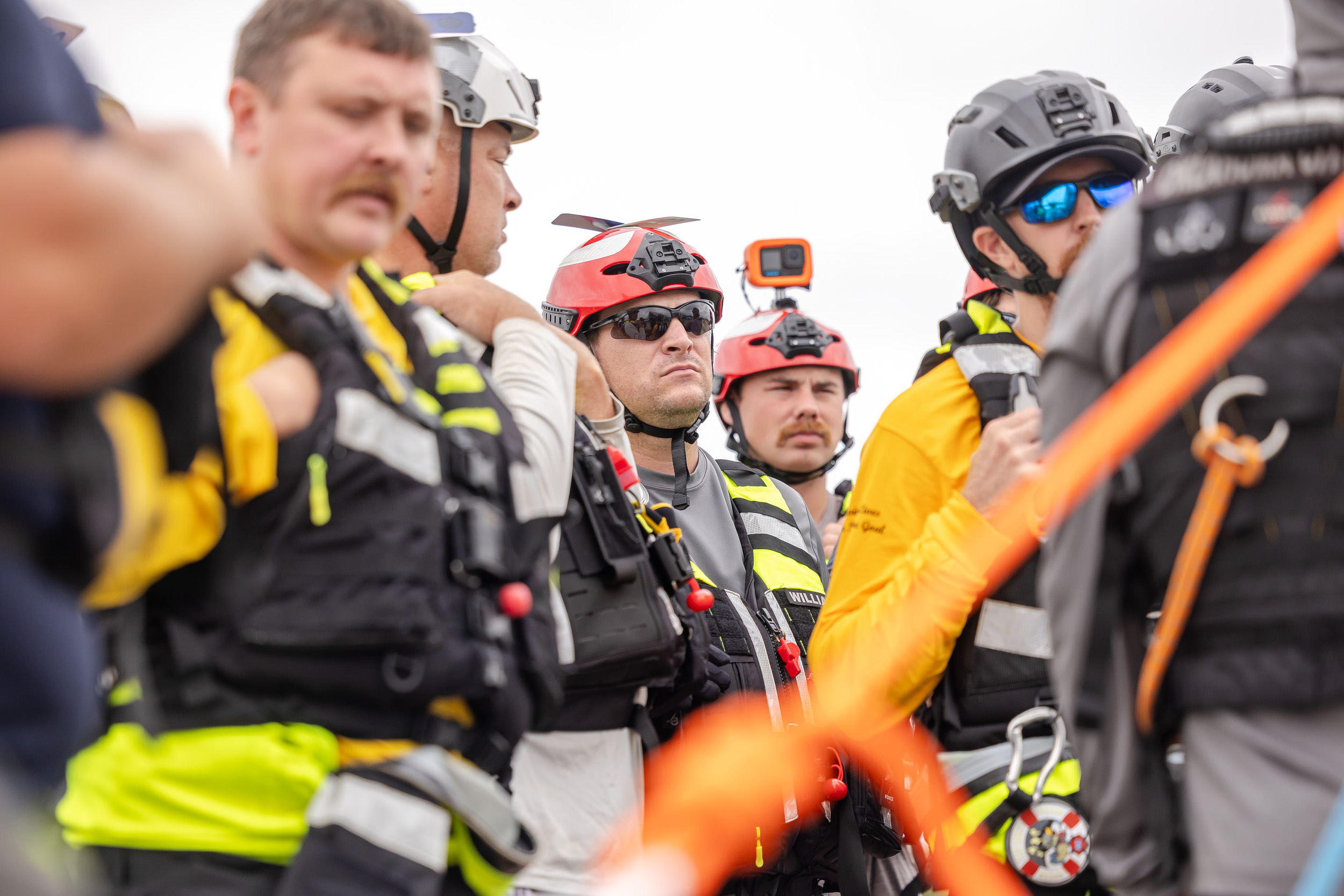A close up shot of a group of individuals dressed in helmets with go pros attached, sunglasses, and life vests.