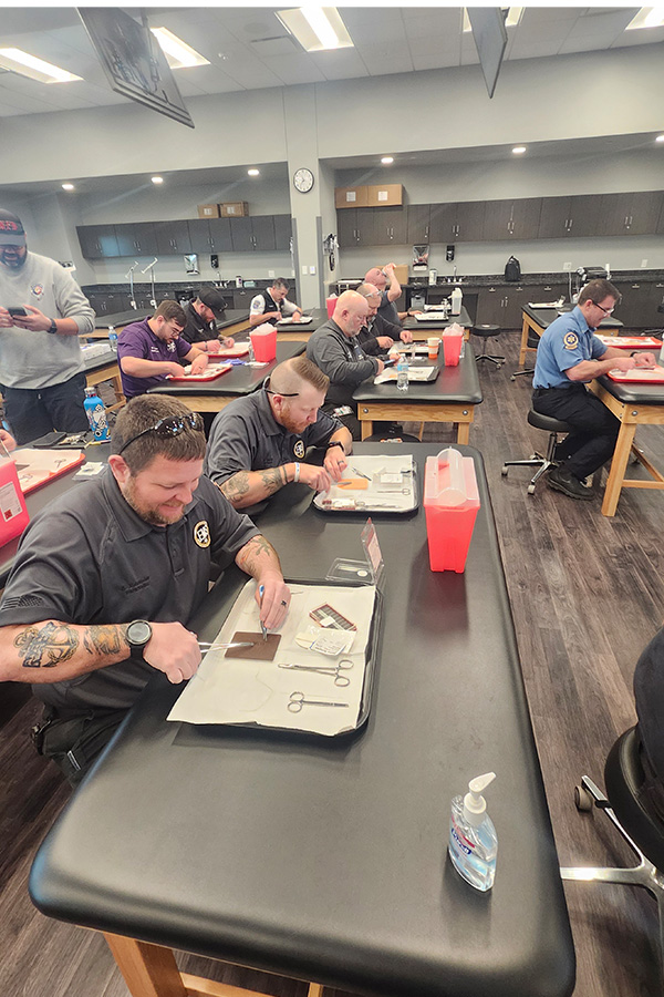 Several men sitting at tables in a classroom, participating in a learning session together.