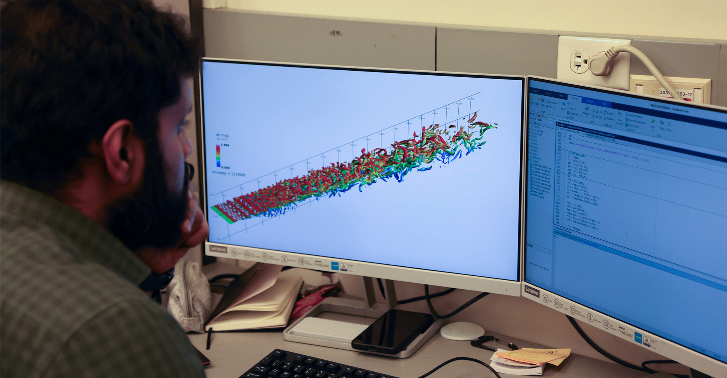 A man with a beard in a laboratory setting works on a computer program that simulates aircraft velocities.