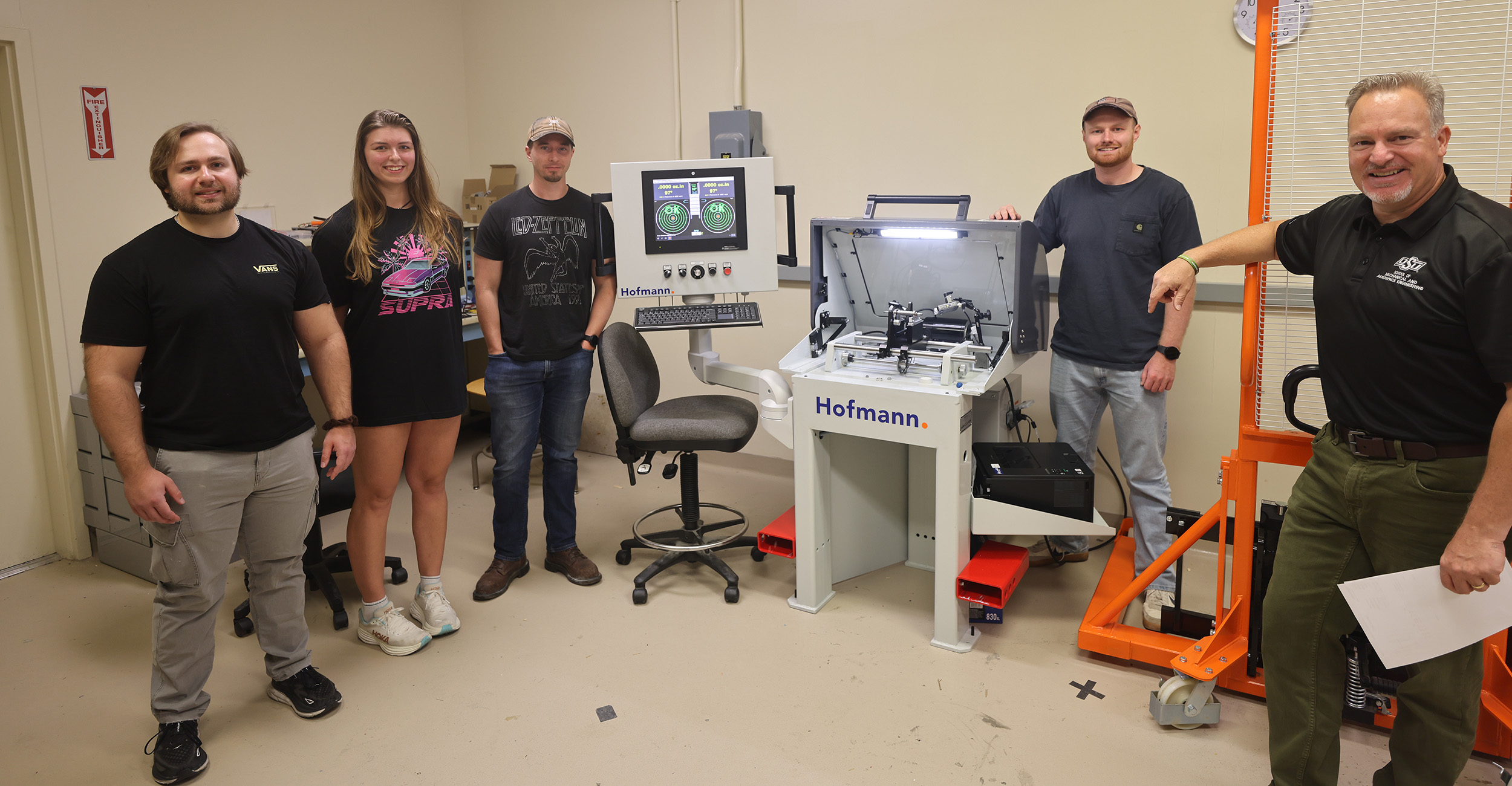Charles Daggett, Alley Boyko, Jared Henderson, Bruce Lamoreaux and Dr. Kurt Rouser stand in a room with equipment used to test propulsion engines. Rouser is a professor of Mechanical and Aerospace Engineering at OSU and the rest are his students.