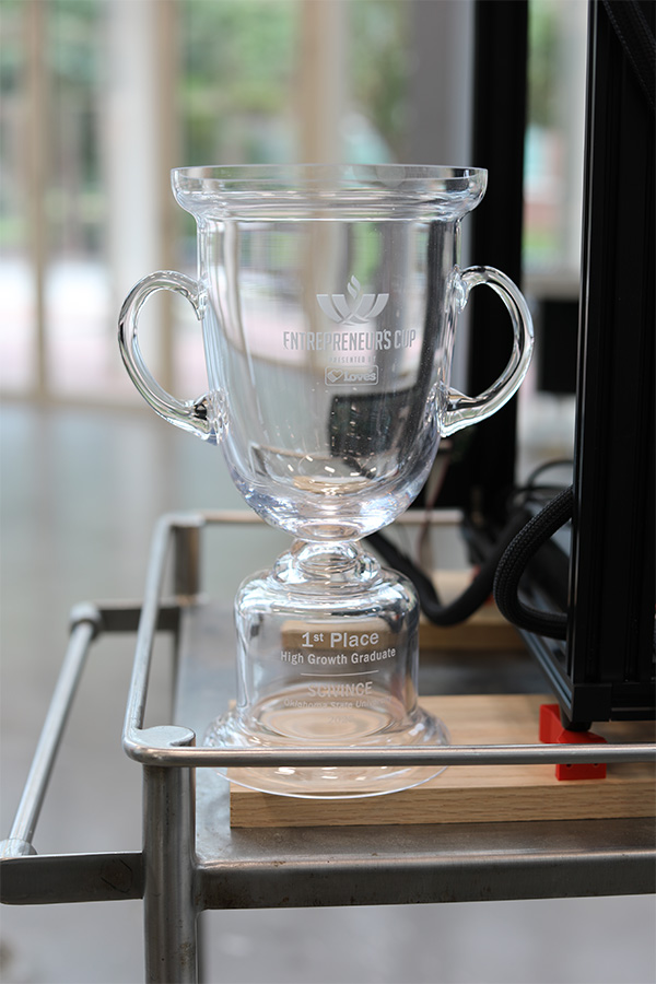 A glass trophy displayed on a metal cart, showcasing its elegant design and reflective surface.