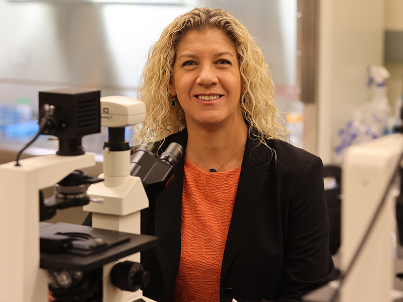 Dr. Heather Fahlenkamp sits at a microskope in her lab