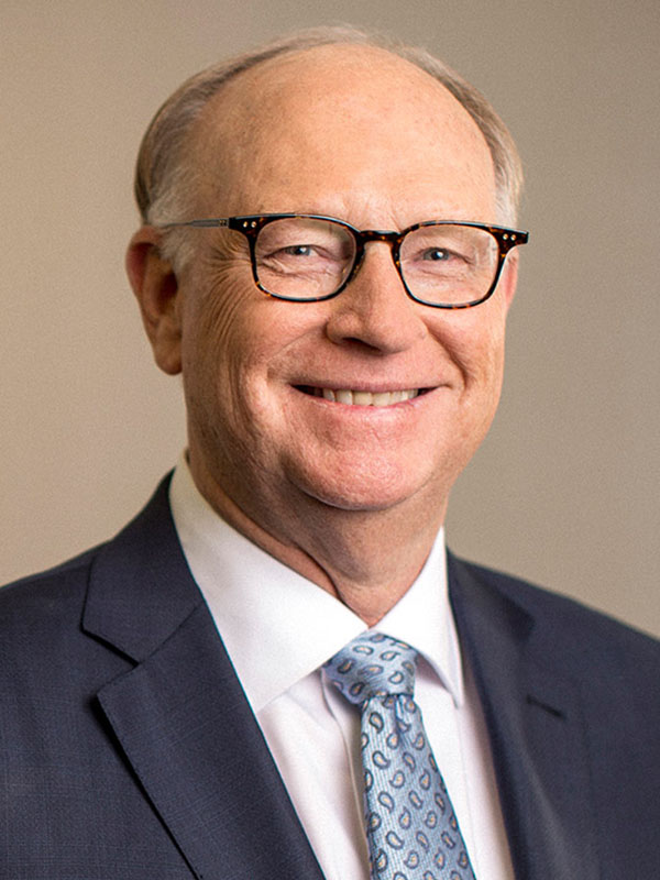 A professional headshot of a smiling man.